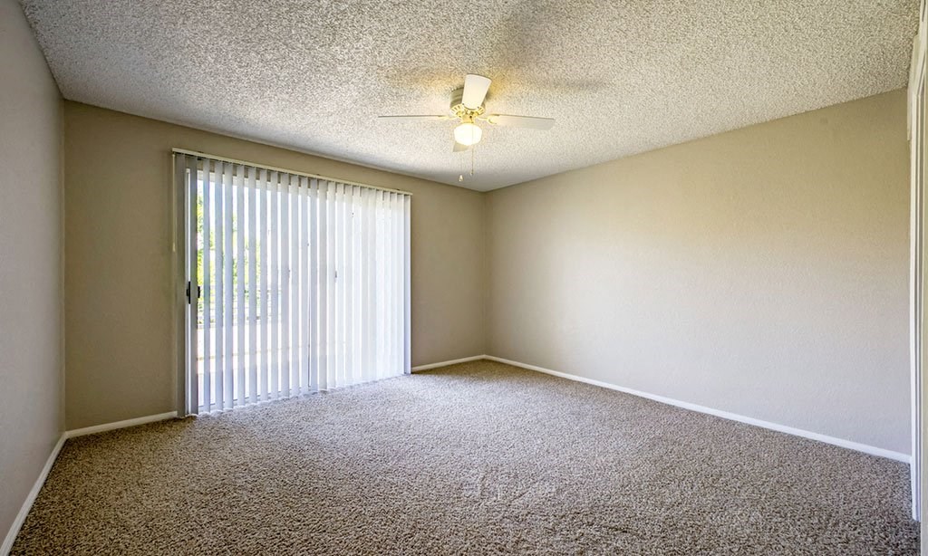 an empty living room with blinds and a ceiling fan
