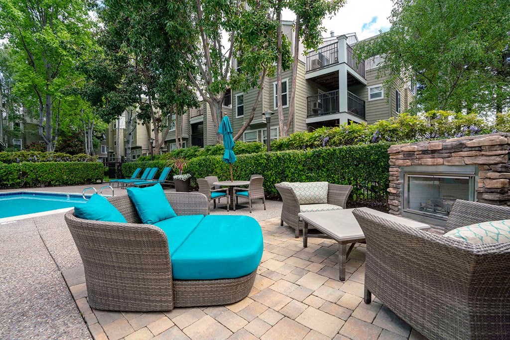 a patio with a pool and chairs and a fireplace