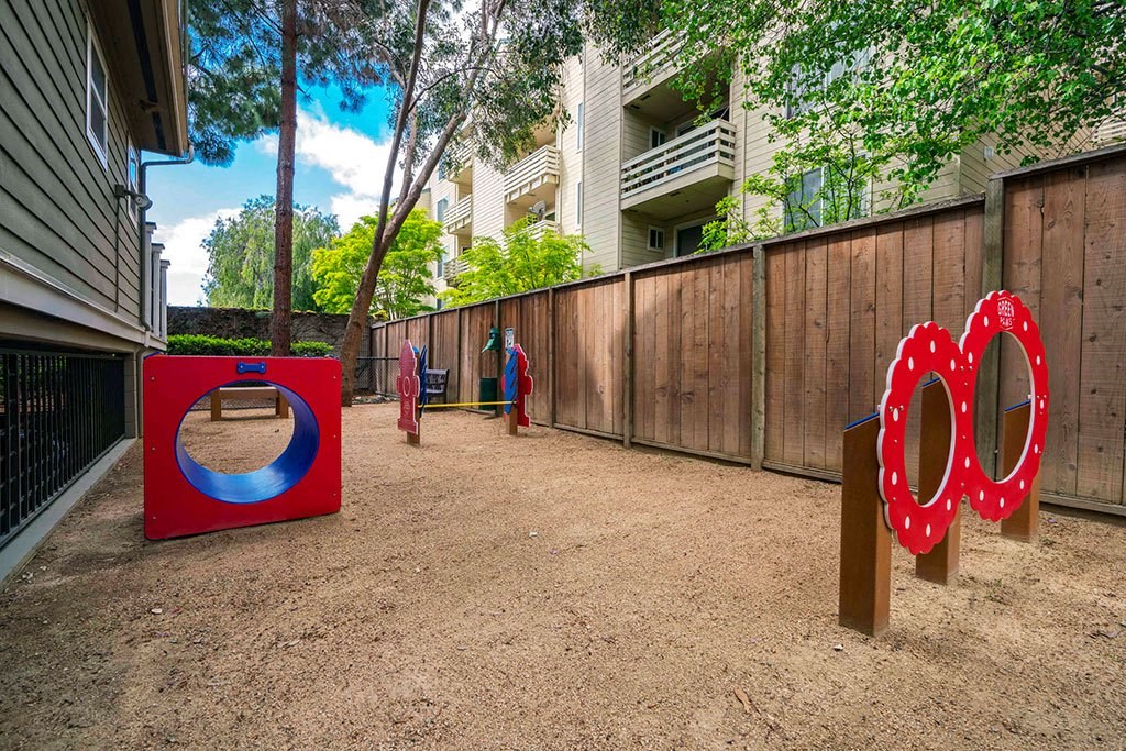 people playing in a playground with targets and a fence