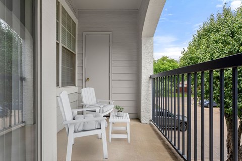 A white chair and table are on a balcony.