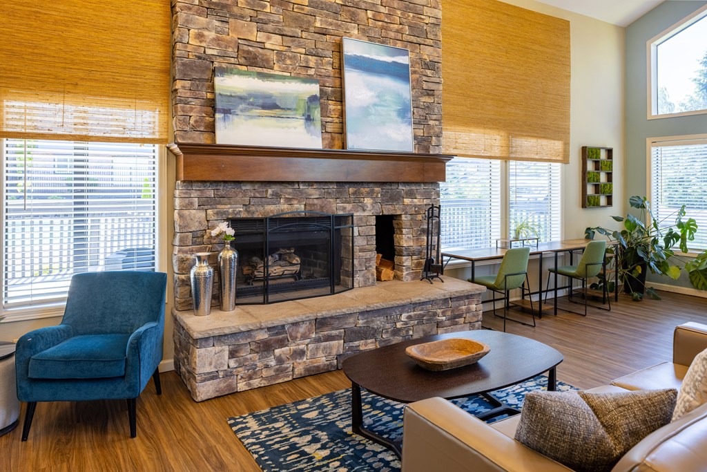 A living room with a stone fireplace and a blue chair.