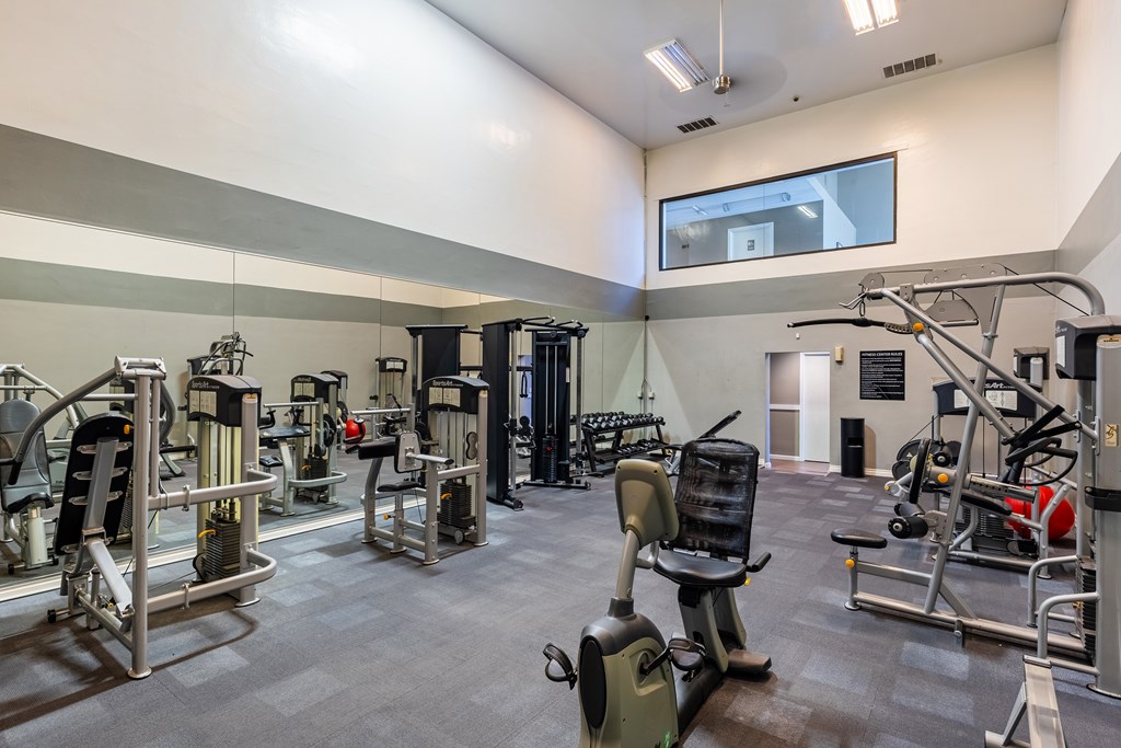 A gym with a variety of equipment including treadmills, weights, and exercise machines.