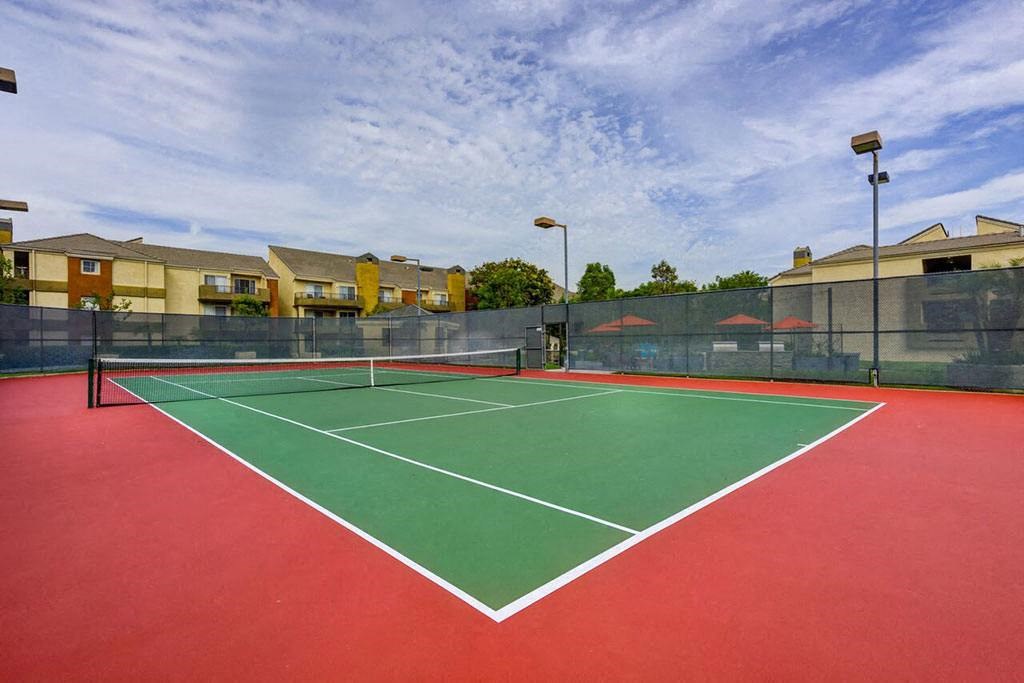 a tennis court with apartments in the background