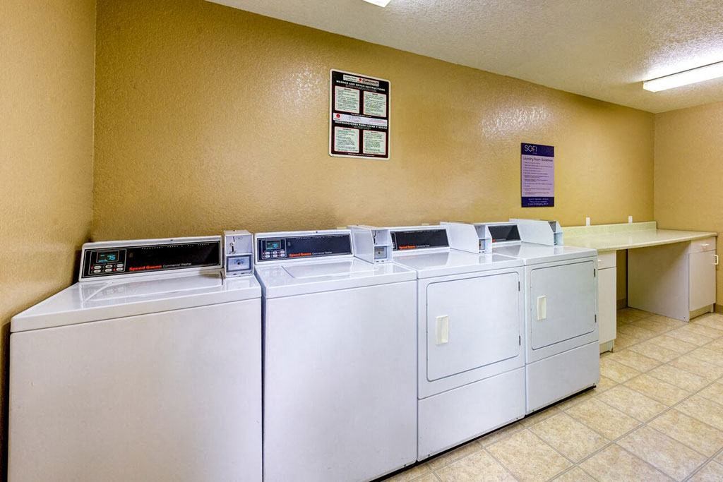 four washing machines are lined up in a laundromat