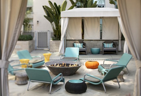 A patio with a fire pit and chairs.