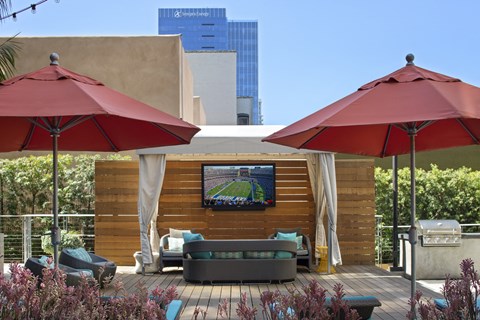 A wooden deck with a TV and two red umbrellas.