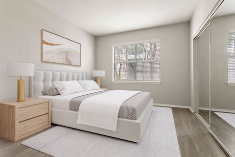 A bedroom with a large bed, a nightstand with a lamp, and a framed picture on the wall.