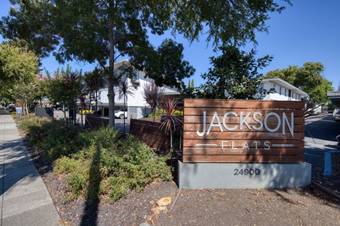 A sign for Jackson Flats is in front of a building.