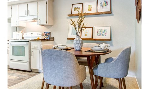 a dining room with a table and chairs and a kitchen with white appliances