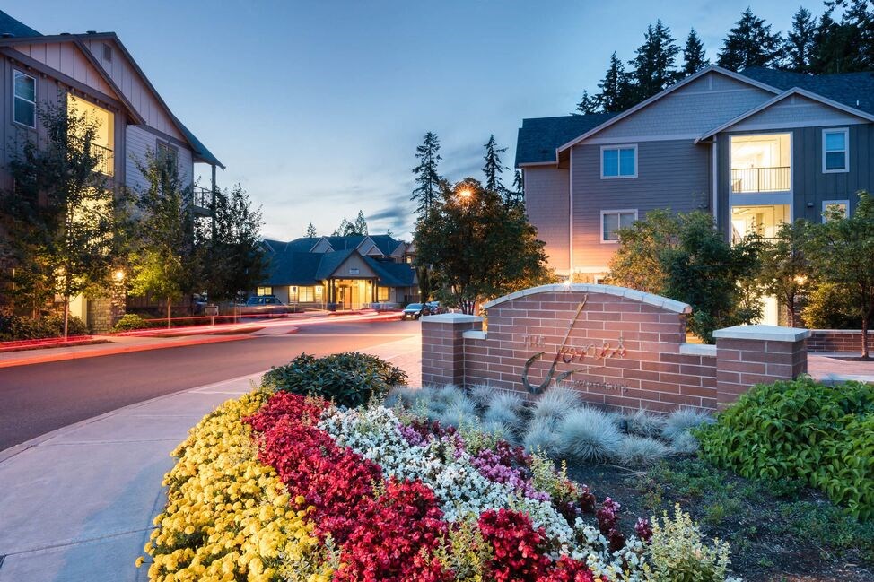 a brick retaining wall with flowers in front of a house