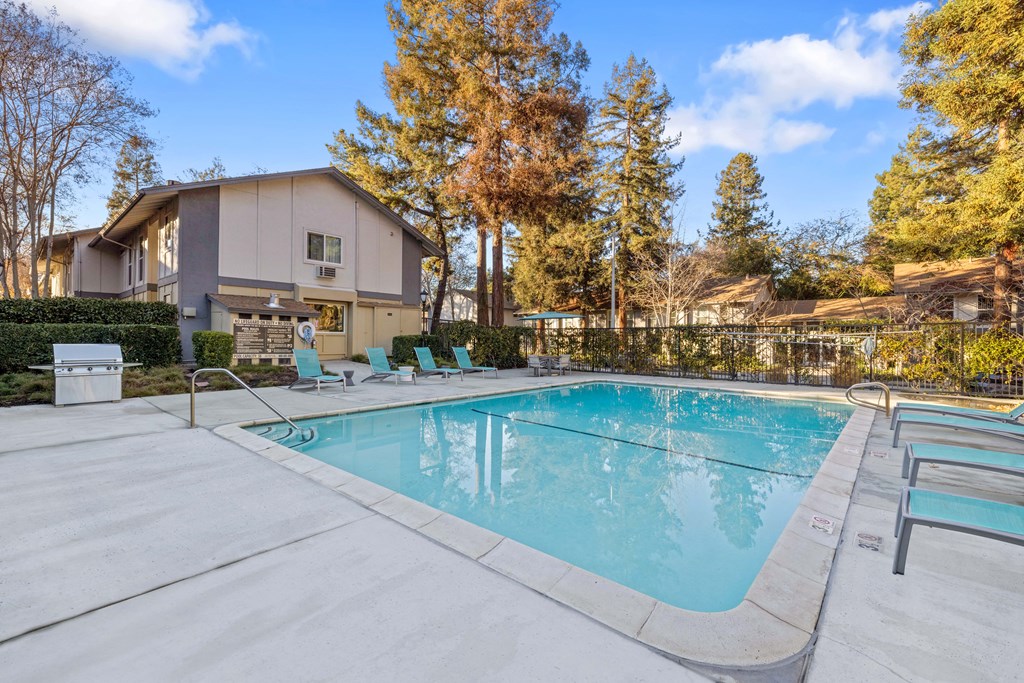 a swimming pool with chairs and a house in the background