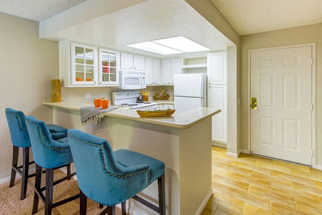 a kitchen with a bar and blue chairs