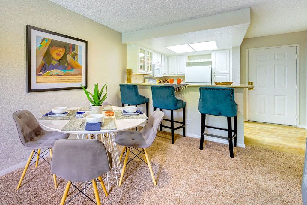a dining room table with chairs and a kitchen in the background