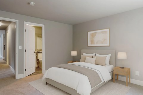 A bedroom with a large bed and a small table with a lamp.