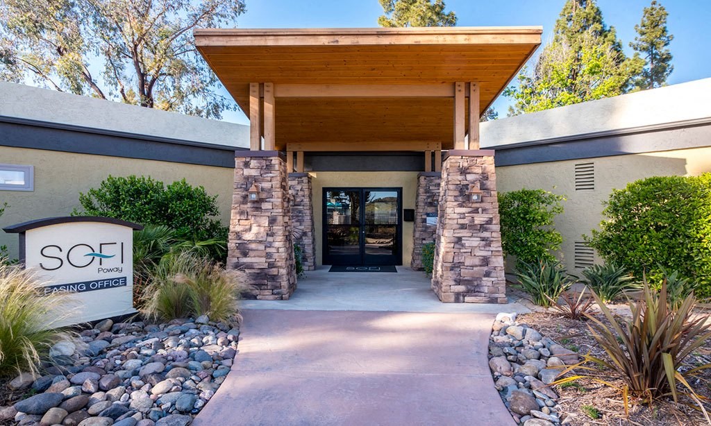 the front entrance of a building with a drive way and a sign