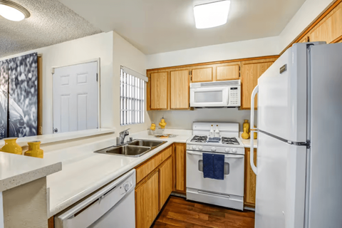 A kitchen with a white fridge, white dishwasher, white sink and white countertops.