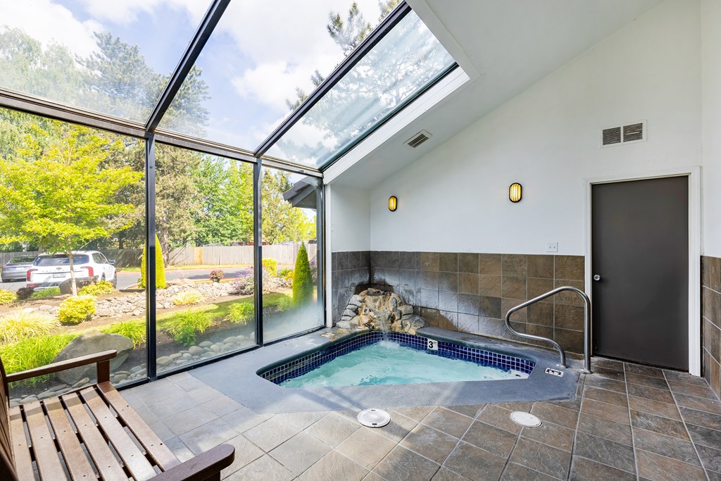 A hot tub is in a room with a glass ceiling.