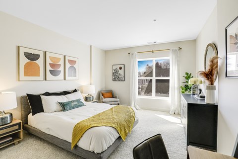 A bedroom with a bed, chair, and pictures on the wall.