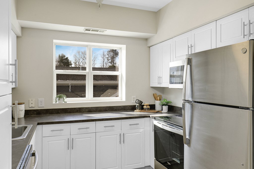 a kitchen with white cabinets and a stainless steel refrigerator