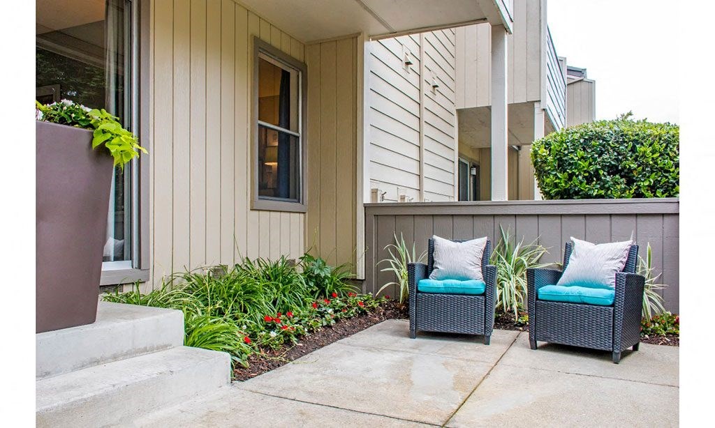 two blue chairs sitting on a patio in front of a house
