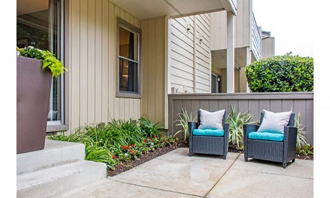 two blue chairs sitting on a patio in front of a house