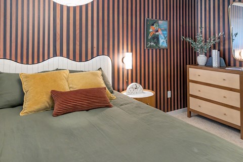 A bedroom with a bed, nightstand, and striped wallpaper.