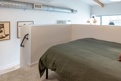 A bedroom with a bed, carpet, and artwork on the wall.