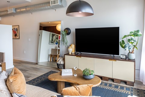 A living room with a large flat screen TV mounted on the wall above a wooden cabinet.