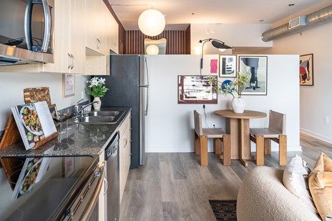 A kitchen with a refrigerator, sink, and a dining table with chairs.