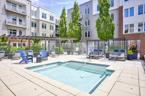 A small pool surrounded by a fence and chairs.