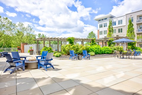 A patio with blue chairs and a fire pit.
