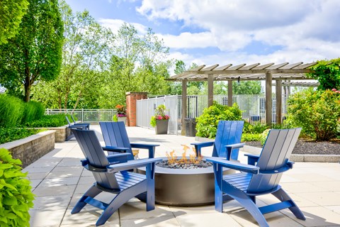 A patio with blue chairs and a fire pit.
