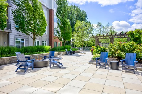 A sunny day at the outdoor seating area of a building with blue chairs and tables.