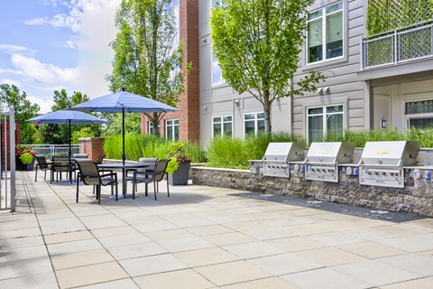 A patio with a table and chairs and a blue umbrella.