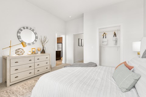 A bedroom with a large bed and a dresser with a mirror above it.