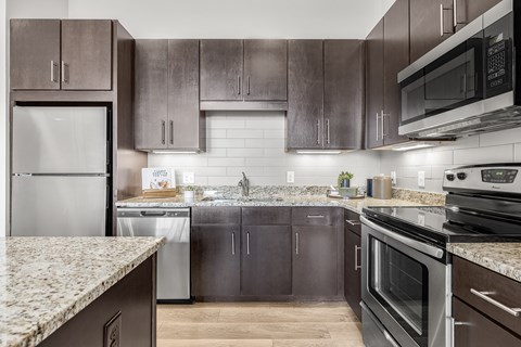 A modern kitchen with dark brown cabinets and stainless steel appliances.
