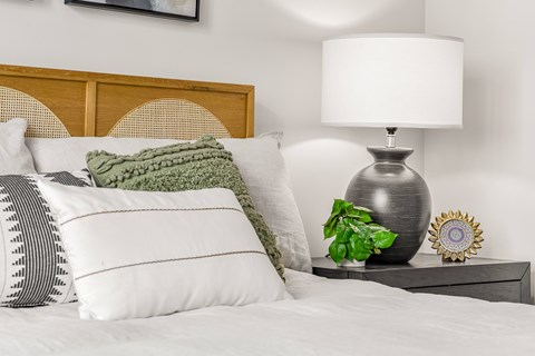 A bed with pillows and a lamp on a nightstand.