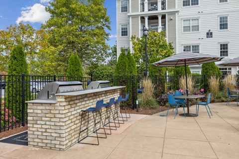 A patio with a brick bar and blue chairs.