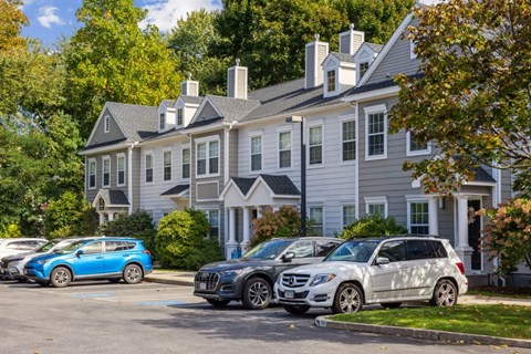 A grey house with a blue car parked in front.
