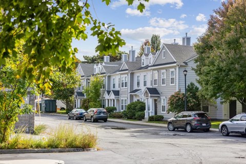 A street view of a residential area with houses and cars.