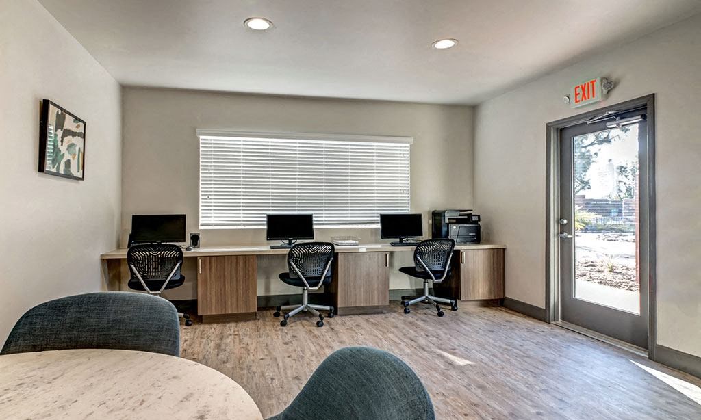 two computer desks in an office with a door and a window