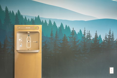 a digital thermostat with a forest of trees in the background