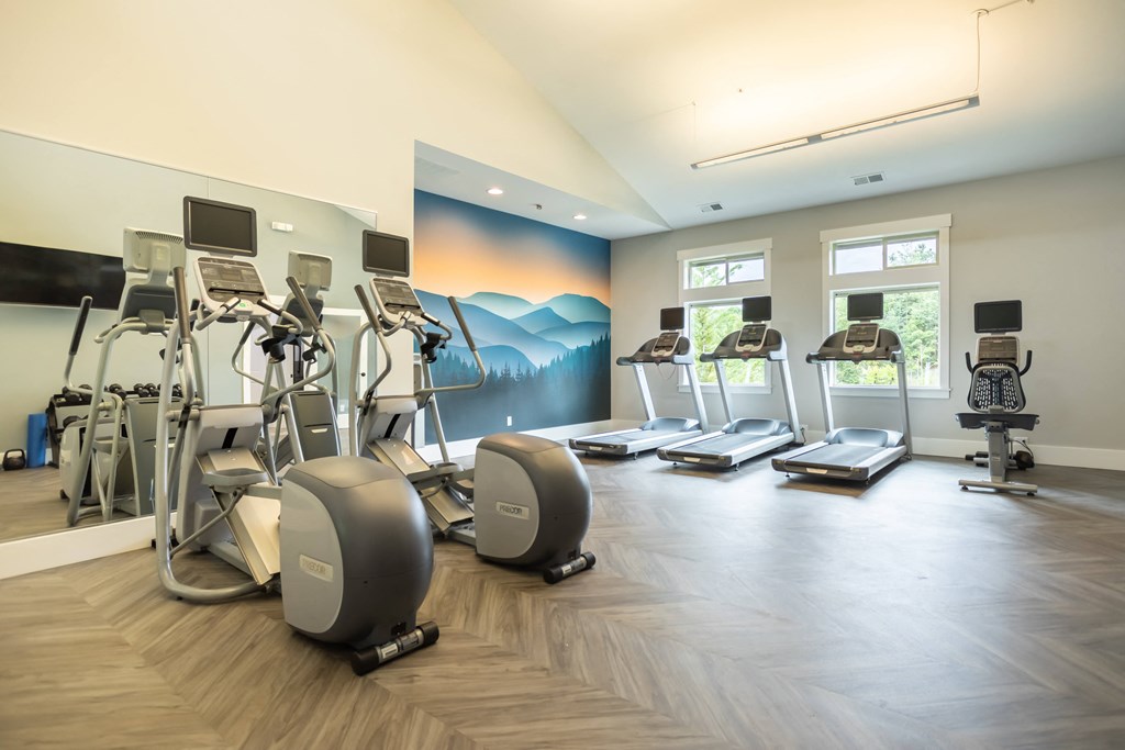 a gym with cardio machines and weights on a wooden floor