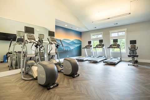 a gym with cardio machines and weights on a wooden floor