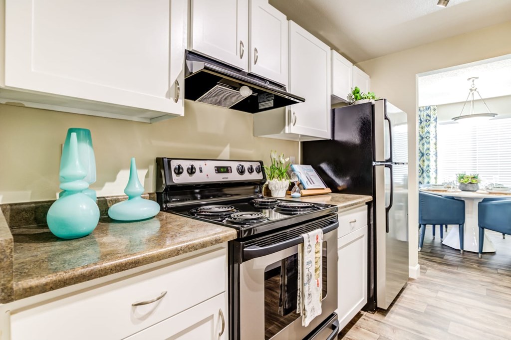 A kitchen with a black stove top oven and white cabinets.