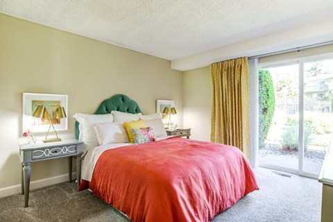 A bedroom with a red bedspread and a green headboard.