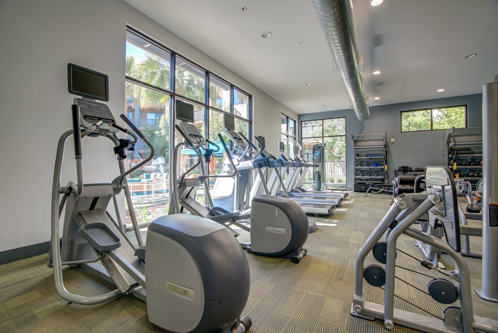 a gym with cardio equipment and windows in a building
