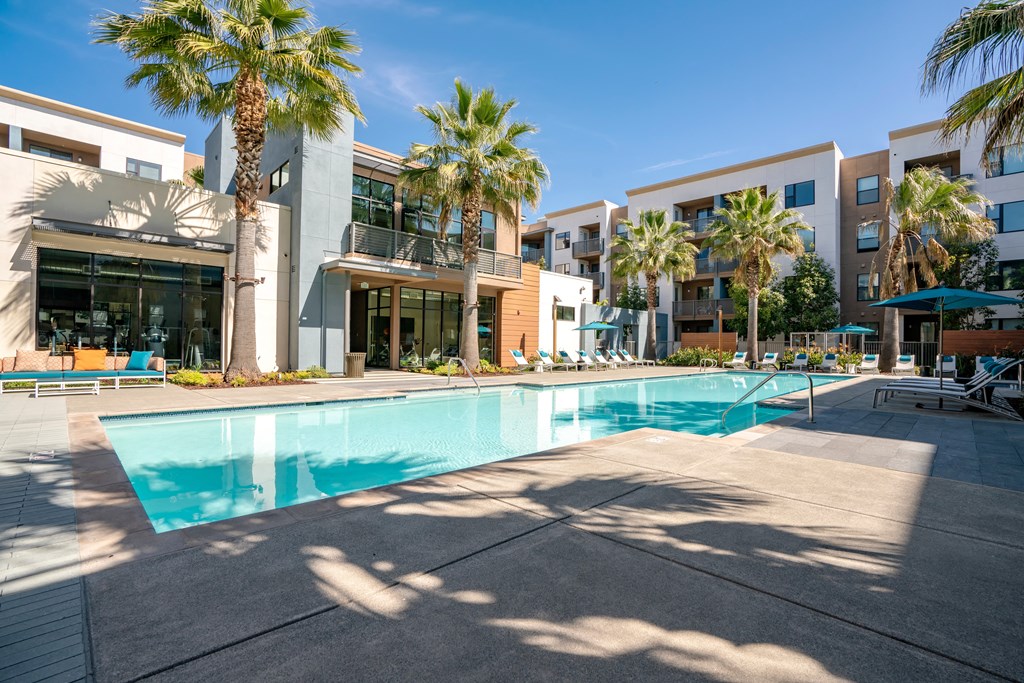 a swimming pool in front of a building with palm trees