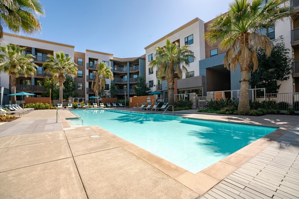 a swimming pool with palm trees in front of an apartment building