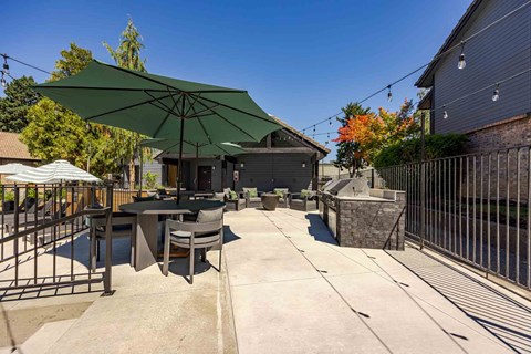 A patio with a table and chairs under a green umbrella.
